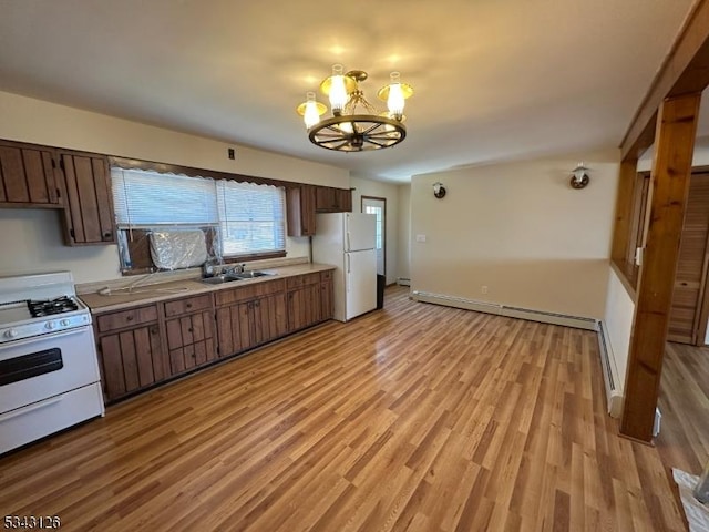 kitchen featuring a sink, a baseboard heating unit, white appliances, and light countertops