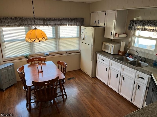 kitchen featuring dark countertops, a sink, white cabinets, white appliances, and dark wood-style flooring