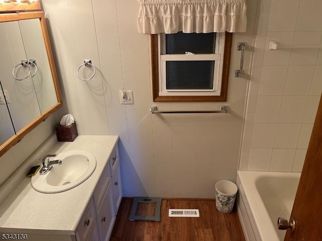 bathroom with visible vents, wood finished floors, a bath, vanity, and a shower