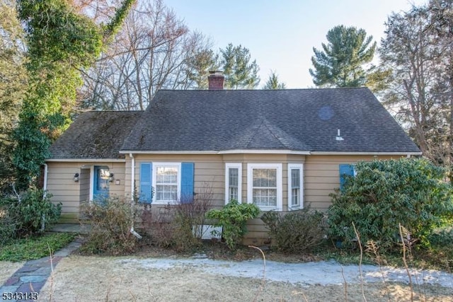 cape cod home featuring roof with shingles and a chimney