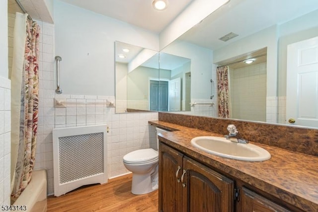 full bath with a wainscoted wall, toilet, wood finished floors, radiator, and tile walls