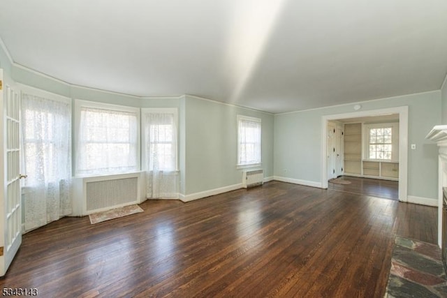 unfurnished living room featuring a fireplace with raised hearth, radiator heating unit, baseboards, and wood finished floors