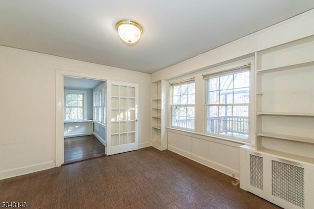 spare room with dark wood finished floors, radiator heating unit, and baseboards