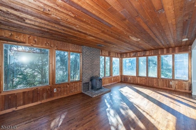 unfurnished sunroom with a wood stove, wood ceiling, and a wealth of natural light