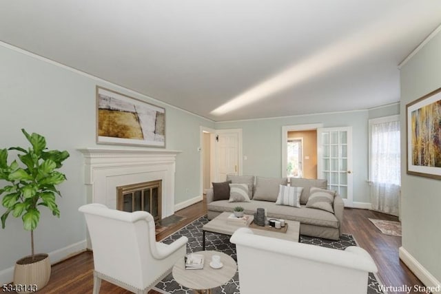 living area featuring a fireplace with flush hearth, baseboards, dark wood-style flooring, and ornamental molding