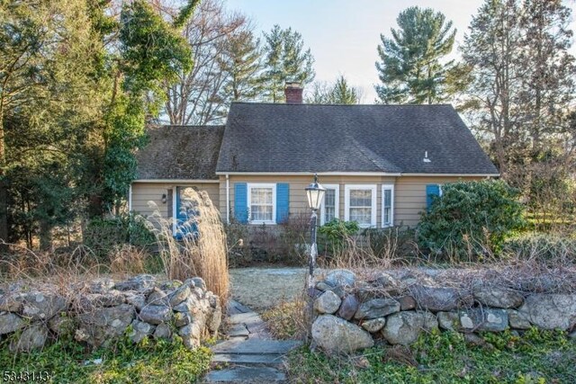 new england style home featuring a chimney and roof with shingles