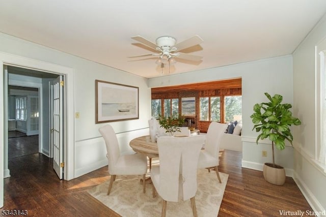 dining space featuring dark wood finished floors, baseboards, and a ceiling fan