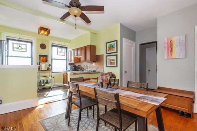 dining room with a ceiling fan, baseboards, and hardwood / wood-style floors