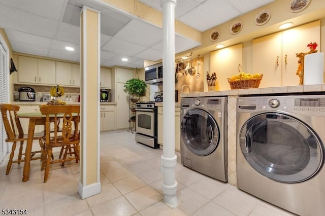 laundry room featuring laundry area, light tile patterned floors, independent washer and dryer, and decorative columns