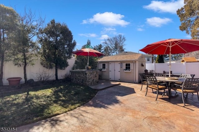 view of patio / terrace featuring an outbuilding, outdoor dining area, and a fenced backyard