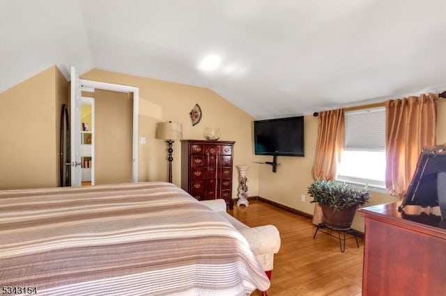 bedroom featuring light wood-style flooring, baseboards, and vaulted ceiling