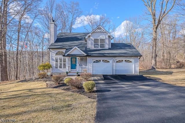 view of front of property with aphalt driveway, a garage, a chimney, and a front yard