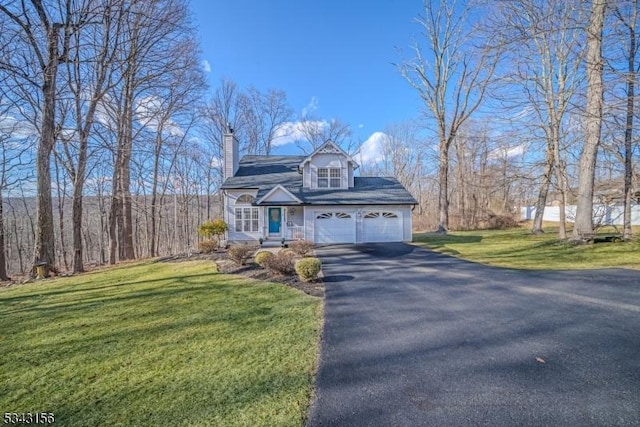 view of front facade featuring a front yard, an attached garage, driveway, and a chimney