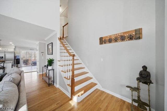 staircase featuring baseboards, wood finished floors, and crown molding