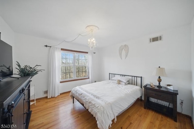 bedroom featuring a notable chandelier, visible vents, and light wood-style floors