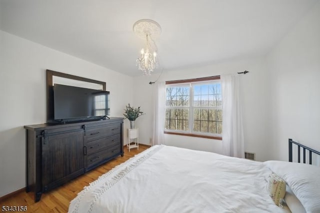 bedroom featuring visible vents, light wood-style floors, and an inviting chandelier