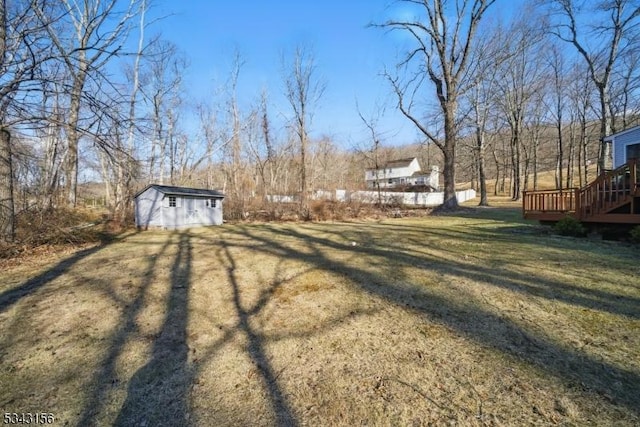 view of yard featuring a storage shed, an outdoor structure, and a wooden deck