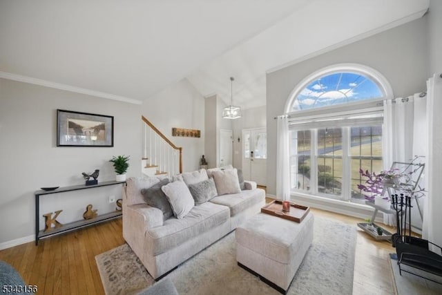 living room with stairway, wood finished floors, baseboards, lofted ceiling, and crown molding