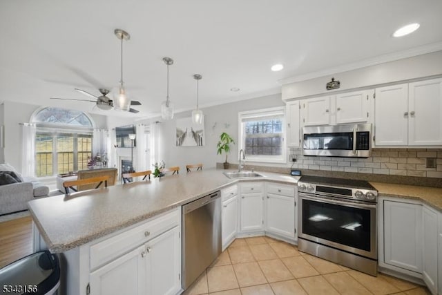 kitchen with a sink, open floor plan, stainless steel appliances, a peninsula, and a fireplace