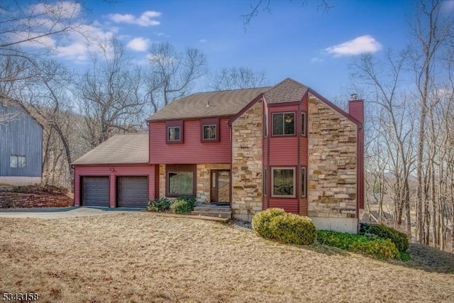 view of front of home with stone siding, an attached garage, a chimney, and driveway