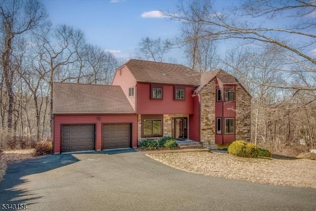 view of front of home with stone siding, driveway, a shingled roof, and a garage