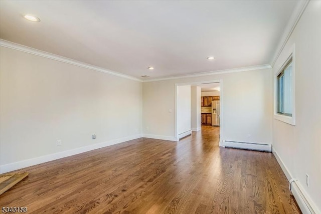 spare room with a baseboard heating unit, wood finished floors, crown molding, baseboards, and baseboard heating