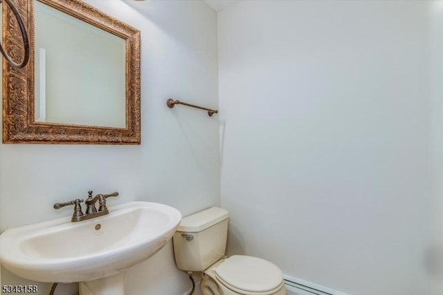 half bath with a baseboard radiator, toilet, and a sink