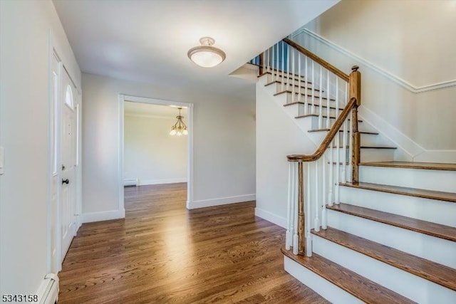 staircase featuring a baseboard heating unit, baseboards, and wood finished floors