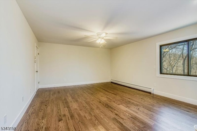 empty room with baseboards, baseboard heating, and wood finished floors