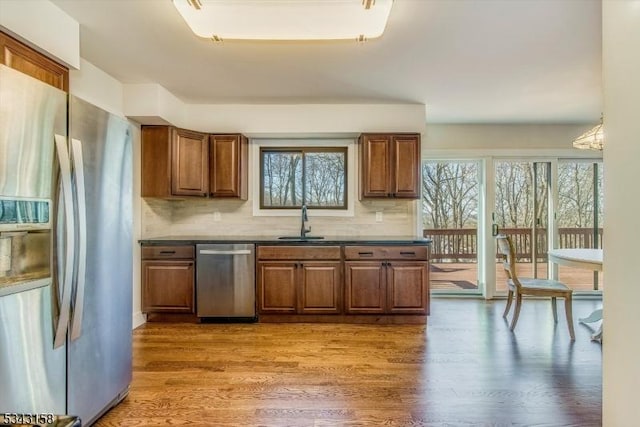 kitchen featuring a sink, brown cabinets, stainless steel appliances, and wood finished floors