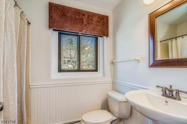 full bathroom with a shower with curtain, toilet, a wainscoted wall, and a sink