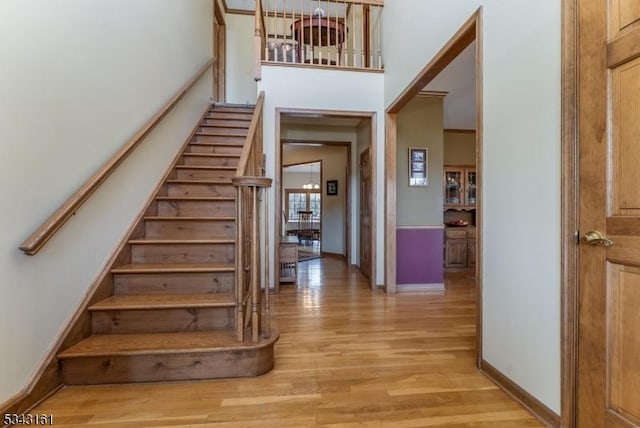 stairway with baseboards, a towering ceiling, and wood finished floors