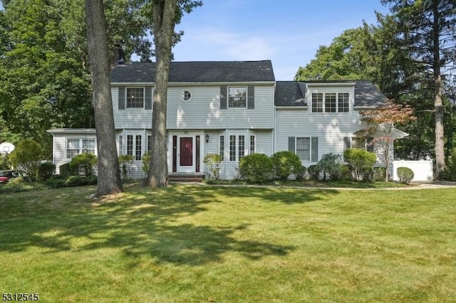 colonial inspired home featuring a front lawn and a chimney