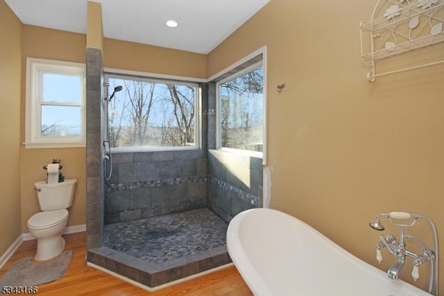 bathroom featuring a freestanding tub, toilet, a healthy amount of sunlight, and wood finished floors