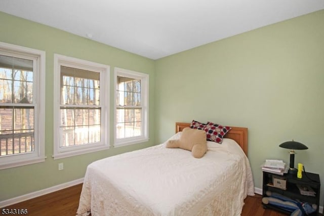 bedroom with dark wood finished floors, multiple windows, and baseboards