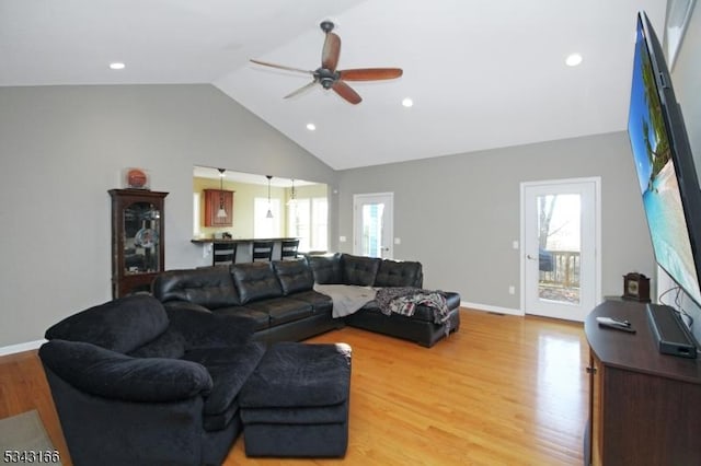 living room with plenty of natural light, light wood-style flooring, baseboards, and ceiling fan