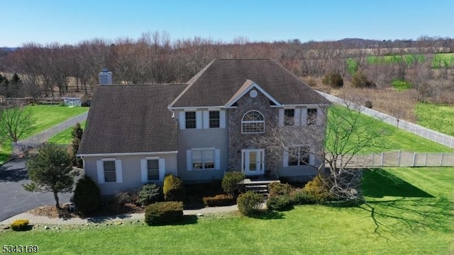 view of front of property with a chimney, a front lawn, and fence