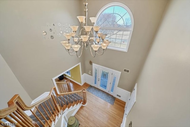 foyer featuring visible vents, baseboards, stairway, wood finished floors, and a notable chandelier