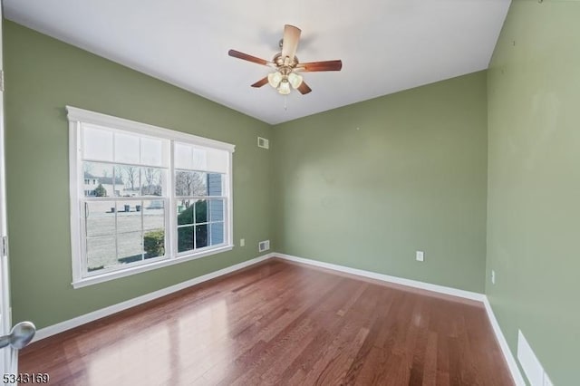 empty room featuring visible vents, a ceiling fan, baseboards, and wood finished floors