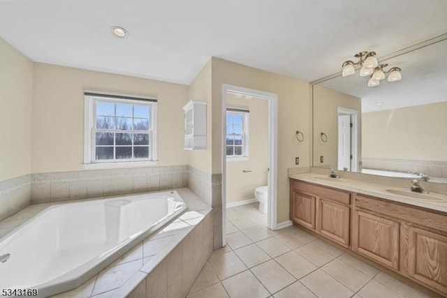 bathroom with a bath, double vanity, toilet, and a sink