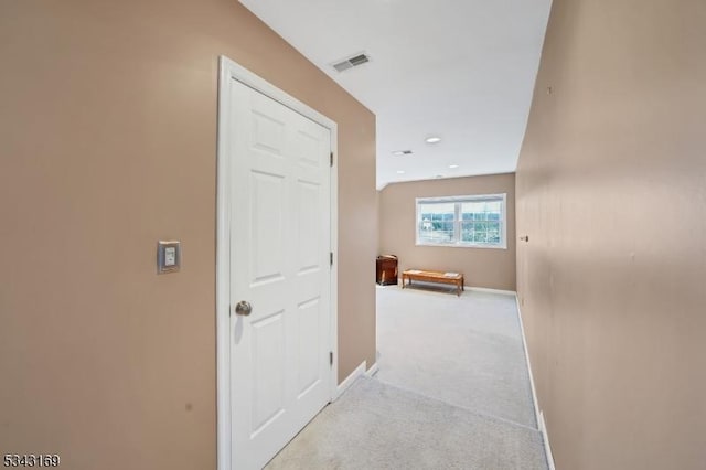 hall featuring visible vents, baseboards, and light carpet