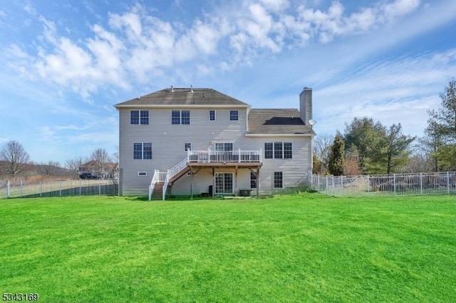 rear view of house featuring stairs, a deck, a lawn, and a chimney