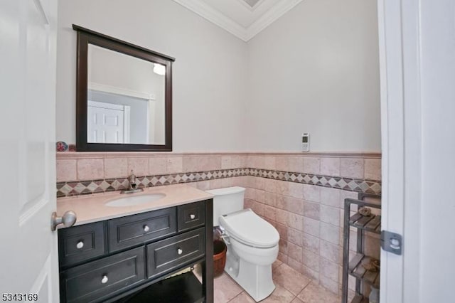 bathroom featuring tile patterned floors, toilet, ornamental molding, wainscoting, and vanity