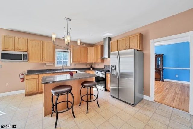 kitchen featuring a sink, stainless steel appliances, light brown cabinets, and wall chimney range hood