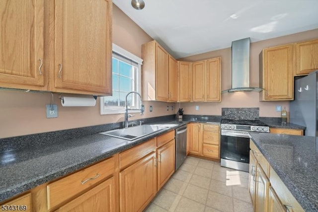 kitchen featuring a sink, dark stone counters, appliances with stainless steel finishes, and wall chimney range hood