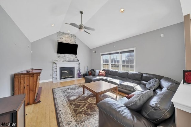 living room featuring high vaulted ceiling, light wood-style floors, ceiling fan, and a fireplace