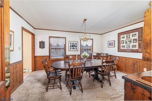 carpeted dining room with wainscoting, an inviting chandelier, crown molding, and wood walls