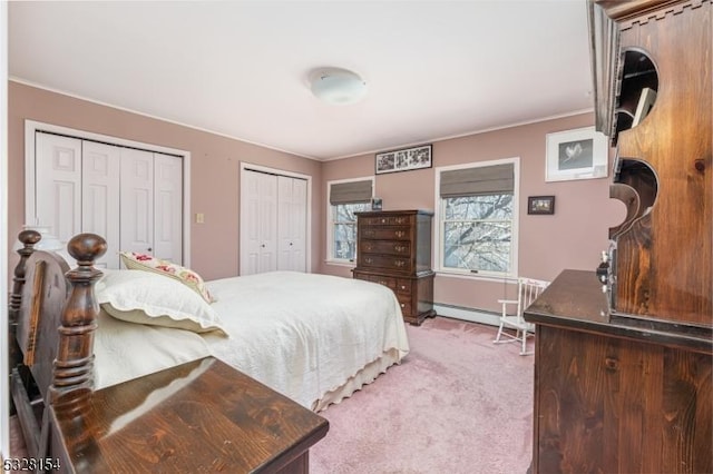 carpeted bedroom featuring a baseboard heating unit, crown molding, and two closets