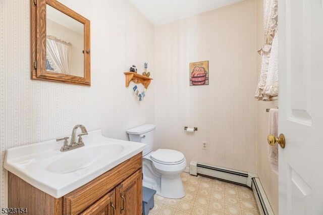 bathroom with toilet, vanity, and a baseboard heating unit