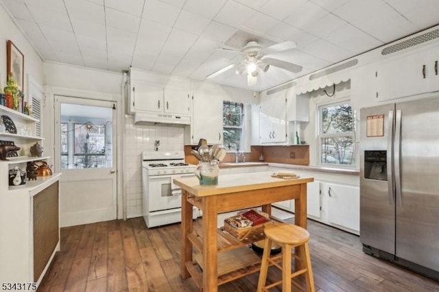 kitchen featuring white gas stove, light countertops, under cabinet range hood, white cabinetry, and stainless steel fridge